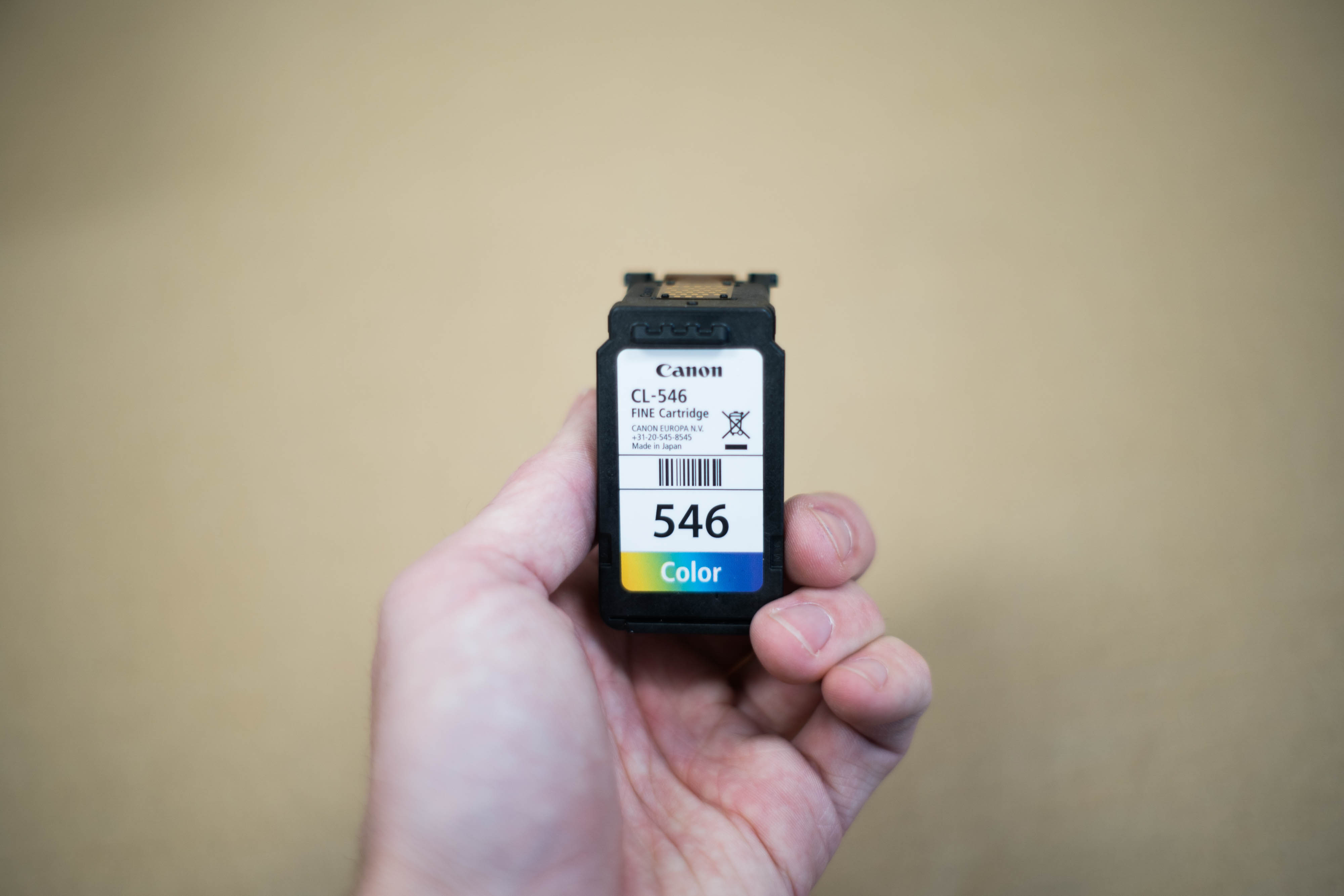close up of a white hand holding an ink jet cartridge